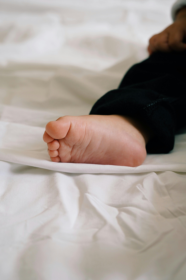 Pied d’un enfant posé sur des draps en coton biologique, illustrant le confort et la douceur d’une literie saine pour les tout-petits.