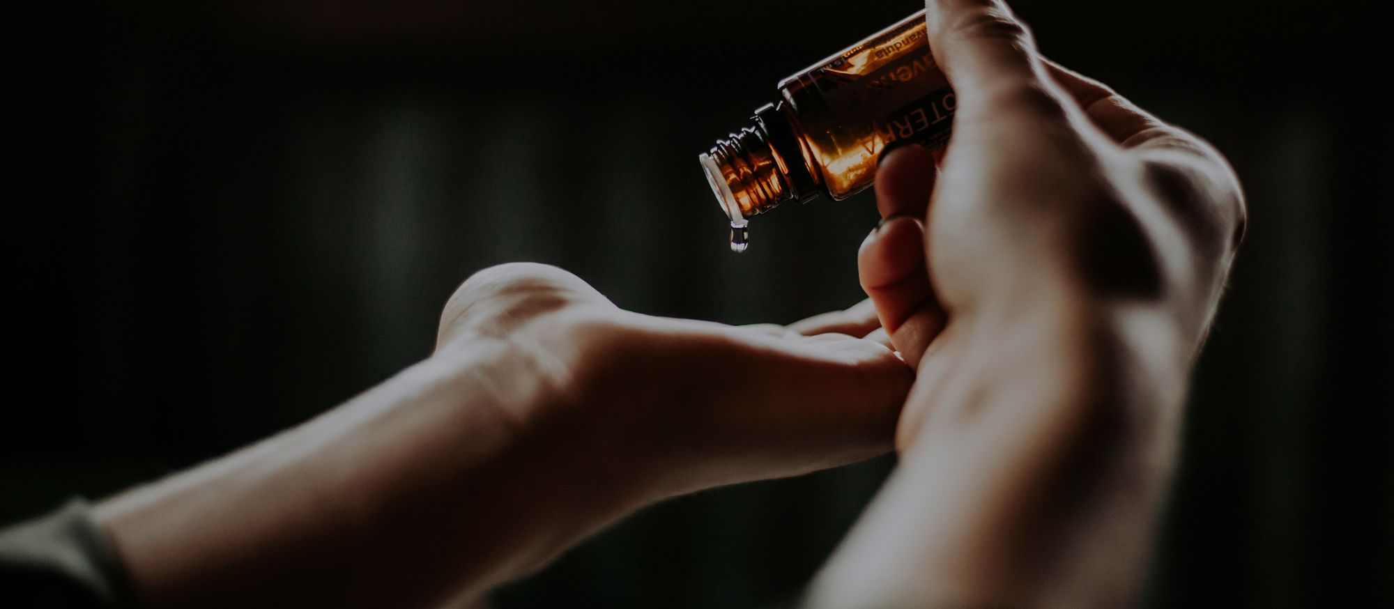 Una goccia di olio essenziale versata sul palmo della mano, in primo piano.