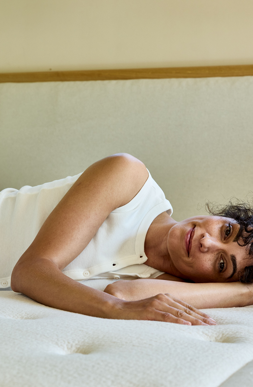 Donna sdraiata su un materasso in lattice naturale Kipli, a dimostrazione del comfort e del sostegno offerti da una biancheria da letto ecologica.