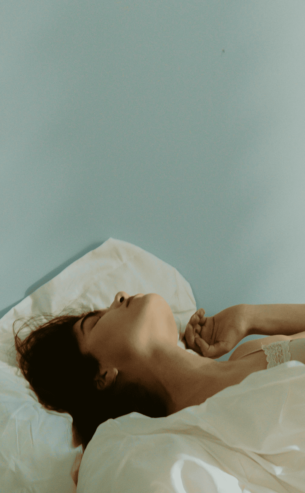 Donna che dorme serenamente in un letto luminoso, a rappresentare un sonno ristoratore e l’atmosfera rilassante della camera da letto.